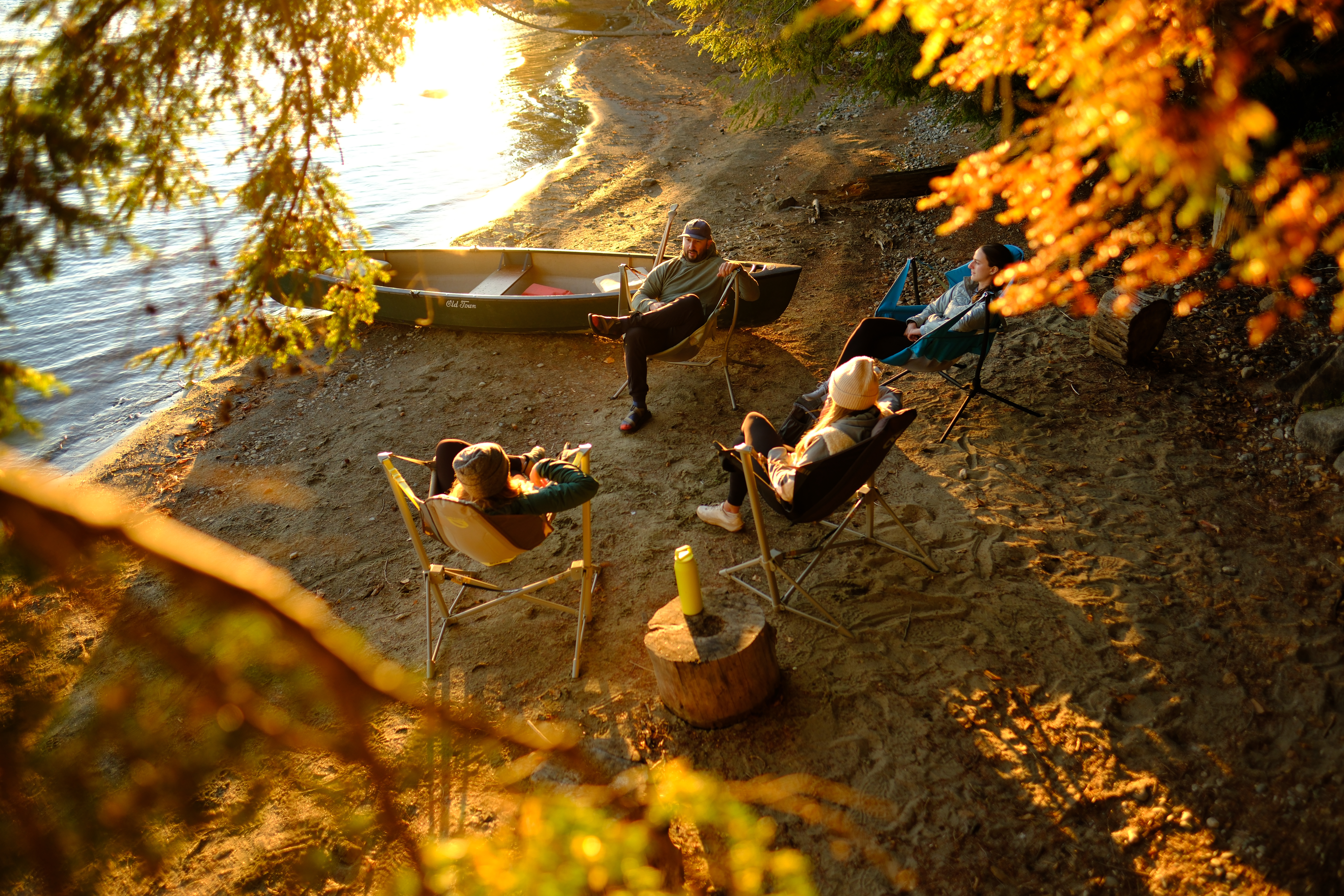 Friends gathered by the water on an autumn camping trip