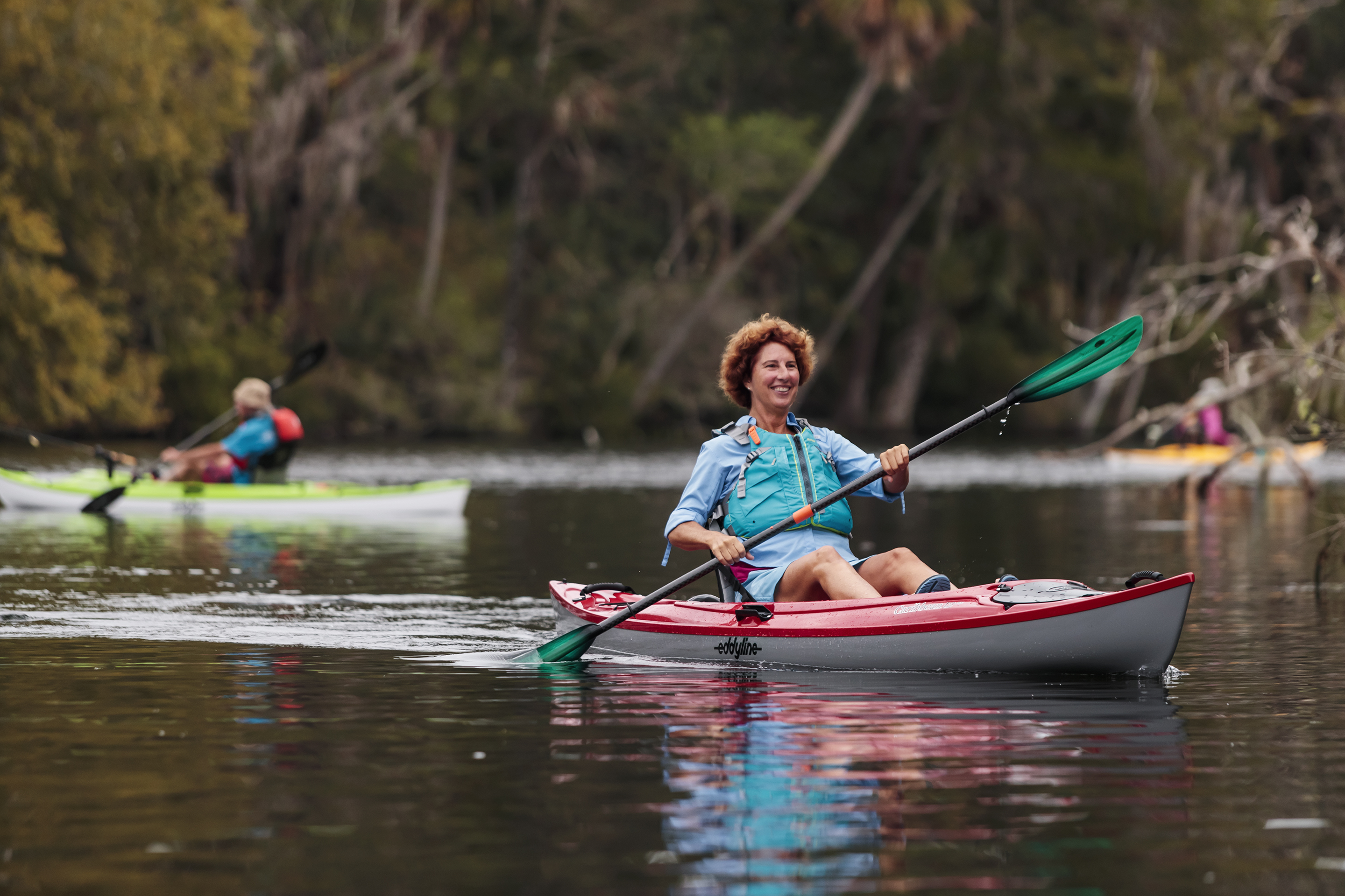 Recreational kayaker paddling on a calm, wooded waterway